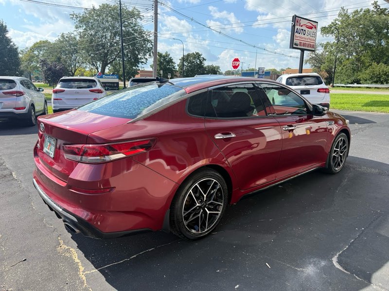 A freshly detailed red Kia Optima parked on the lot.