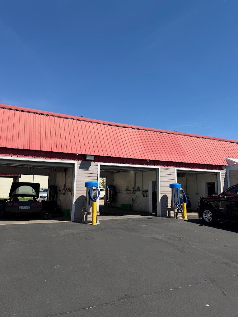 The MG Auto Detailing shop: a building with a red metal roof and three open service bays.